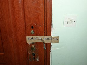 drzwi do mieszkania bez klamki z naklejoną taśmą z napisem Policja