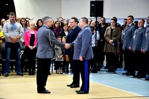 Komendant Wojewódzki Policji w Białymstoku gratuluje nowemu komendantowi policji w Sokółce. W tle kierownictwo policji i rodziny nowoprzyjętych policjantów.