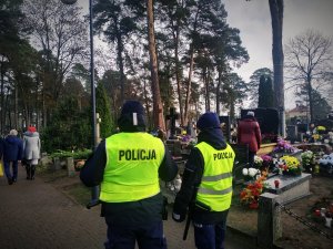 umundurowani policjanci w żółtych kamizelkach podczas patrolu cmentarza
