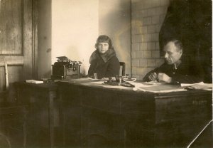 zdjęcie przedstawiające mężczyznę w mundurze, obok siedząca kobieta. zdjęcie dawne