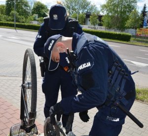 Policjanci sprawdzają seryjne numery roweru.