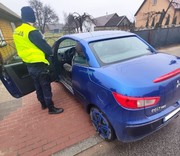 policjant stoi przy niebieskim pojeździe w środku siedzi kierowca