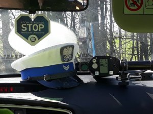 policyjna czapka z ruchu drogowego, obok leżący radar do ręcznego pomiaru prędkości