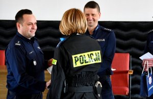 dwóch policjantów, którzy wręczają nagrodę policjantce