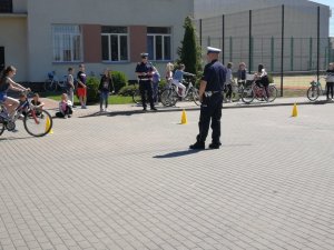 Zdjęcie w kolorze. Policjant egzaminuje dzieci pod kątem uzyskania karty rowerowej.