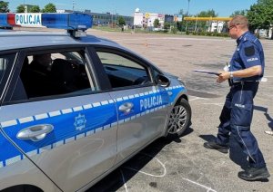 policjant w mundurze stoi przy samochodzie policji