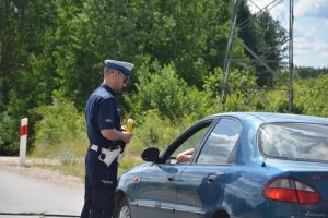 Policjant stojący przy samochodzie z urządzeniem do badania stanu trzeźwości