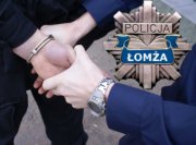 Policjant zakłada kajdanki zatrzymanemu po prawej stronie odznaka policyjna z napisem Łomża.