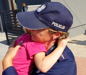 Dziecko w objęciach policjantki.
