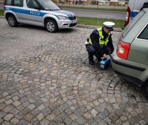 policjant podczas sprawdzania emisji spalin w pojeździe