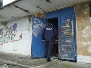 mężczyzna w granatowym mundurze z napisem policja wchodzi przez drzwi do budynku