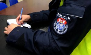 policjant piszący w notatniku służbowym