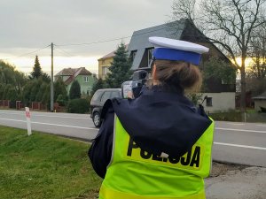 policjantka ubrana w kamizelkę odblaskową podczas pomiaru prędkości