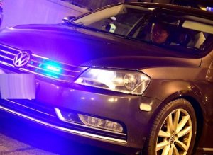 Nieoznakowany radiowóz policji marki VW z włączonymi światłami błyskowymi zaparkowany w tunelu.