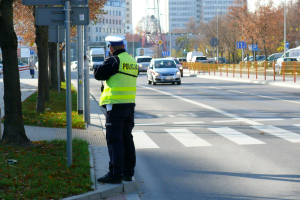 policjant stojący tyłem na poboczu podczas pomiaru prędkości