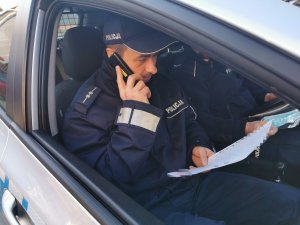 umundurowany policjant w samochodzie rozmawia przez telefon
