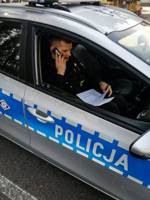 policjant w radiowozie; rozmawia przez telefon