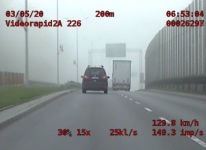 widok pojazdu jadącego drogą, na ekranie napisy
