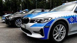 Radiowozy marki BMW oznakowane i nieoznakowane ustawione na parkingu przy ulicy.