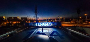 widok z góry pojazdu policji nocą na dachu oświetlona belka z napisem policja