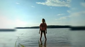 Dziewczynka stoi nad brzegiem wody.