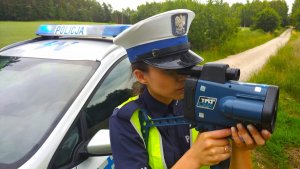 Policjantka ruchu drogowego mierzy prędkość laserowym miernikiem.