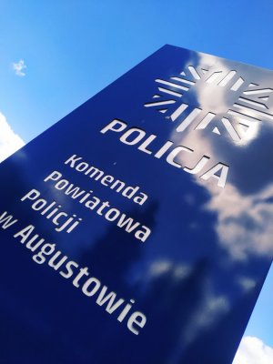 Baner przed komendą z napisem komenda powiatowa policji w Augustowie.