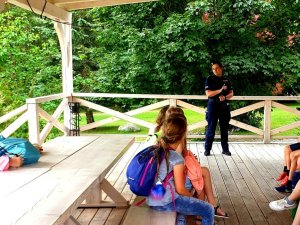 policjantka rozmawia z grupą dzieci, które siedzi na ławce