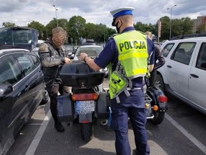 policjant w żółtej kamizelce stoi za kontrolowanym motocyklem obok stoi kierowca