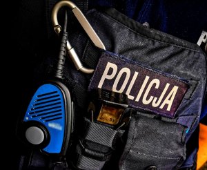 ciemna kamizelka z napisem policja przy napisie niebieska manetka radiostacji