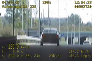 Widok z kamery zainstalowanej w radiowozie. Widać samochód, którego kierowca przekracza prędkość.