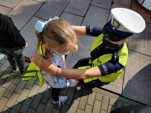 Policjantka ruchu drogowego nakłada kamizelkę odblaskową dla dziecka.