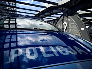 radiowóz ; widać napis policja na masce samochodu; w tle niebo i most