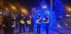 Policjantki stoją wraz z innymi osobami obok świecących na niebiesko obiektach.