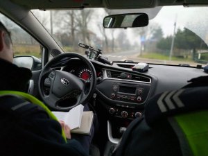 wnętrze pojazdu za kierownica siedzi policjant