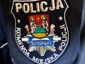 Naszywka z logo Komendy Miejskiej Policji w Suwałkach na przedramieniu policyjnej kurtki
