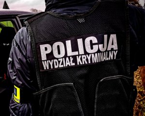 policjant kryminalny na zewnątrz; na kamizelce taktycznej koloru czarnego napis policja wydział kryminalny