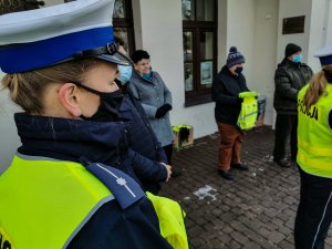 Podlascy policjanci z Wydziału Ruchu Drogowego wspólnie z przedstawicielami Wojewódzkiego Ośrodka Ruchu Drogowego w Białymstoku i burmistrzem Supraśla podczas przekazania pracownikom socjalnym oraz przedstawicielom lokalnego stowarzyszenia seniorów około 100 odblaskowych plecaków.