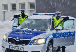 Policjanci przy radiowozie w zimowej aurze.