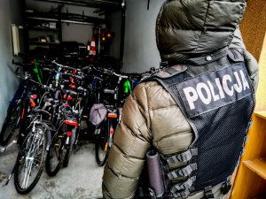 Garaż z odzyskanymi rowerami, na które patrzy policjant