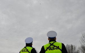 dwóch policjantów na zewnątrz obserwuje drona