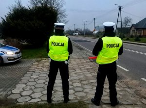 Dwóch policjantów stoi przy drodze.