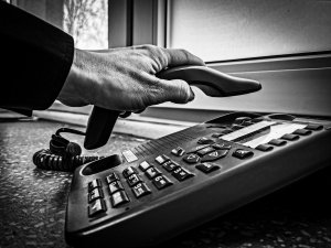 osoba starsza odkłada słuchawkę telefonu stacjonarnego; zbliżenie na jej rękę; zdjęcie czarno-białe