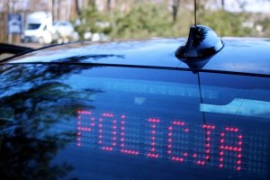 czerwony napis policja widoczny przez szybę nieznakowanego policyjnego samochodu