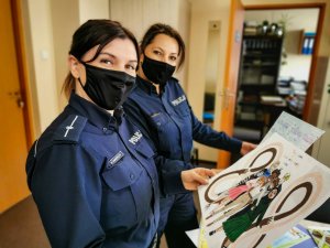 dwie policjantki trzymają konkursowe prace plastyczne