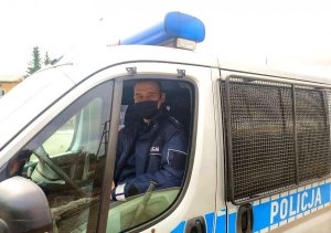 Policjant siedzi za kierownicą radiowozu.