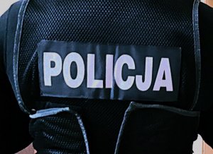 zbliżenie na plecy policjanta w kamizelce taktycznej; widoczny napis Policja