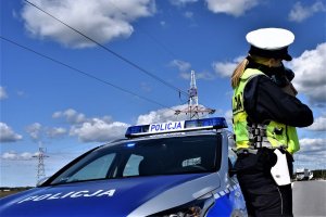 policjantka dokonuje pomiaru prędkości; w tle droda i samochody