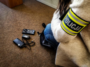 kobieta pochylona nad podłogą na podłodze urządzenia elektroniczne na ramieniu kobiety opaska z napisem policja