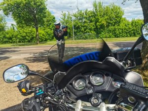 policjant przy drodze na pierwszym planie widok na motocykl